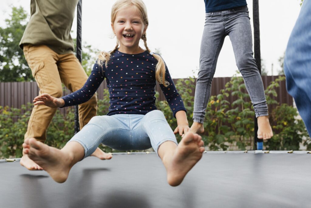 giwa-bambini-su-trampolino-elastico-focus-su-bambina-sorridente-con-trecce-bionde