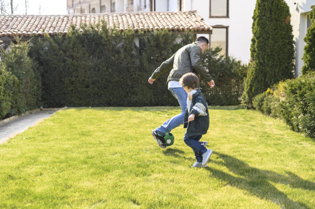 giwa-bambino-gioca-a-calcio-con-papà-su-tappeto-di-erba-sintetica